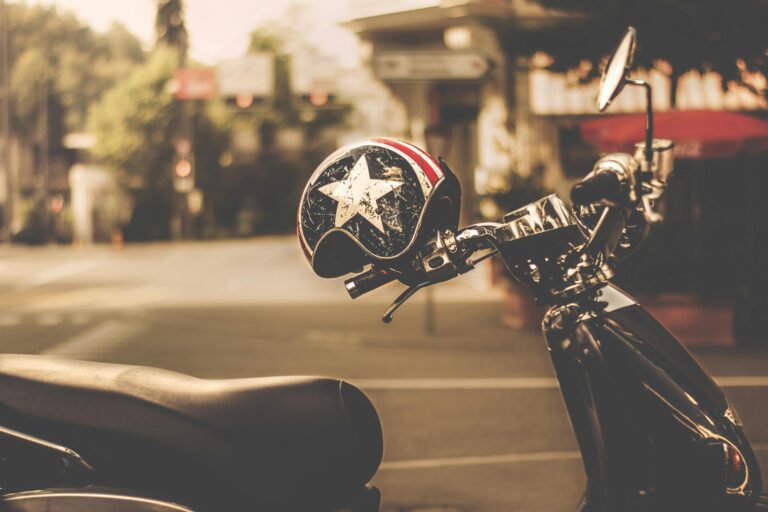 A vintage-style helmet rests on a scooter in a sunlit urban environment.