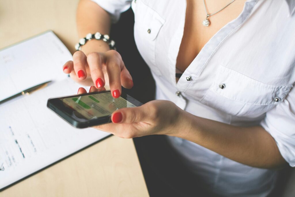Đừng Để Tin Nhắn Làm Nhăn Cái Uy Tín Close-up of a woman with red nail polish using a smartphone indoors, showcasing technology and lifestyle.