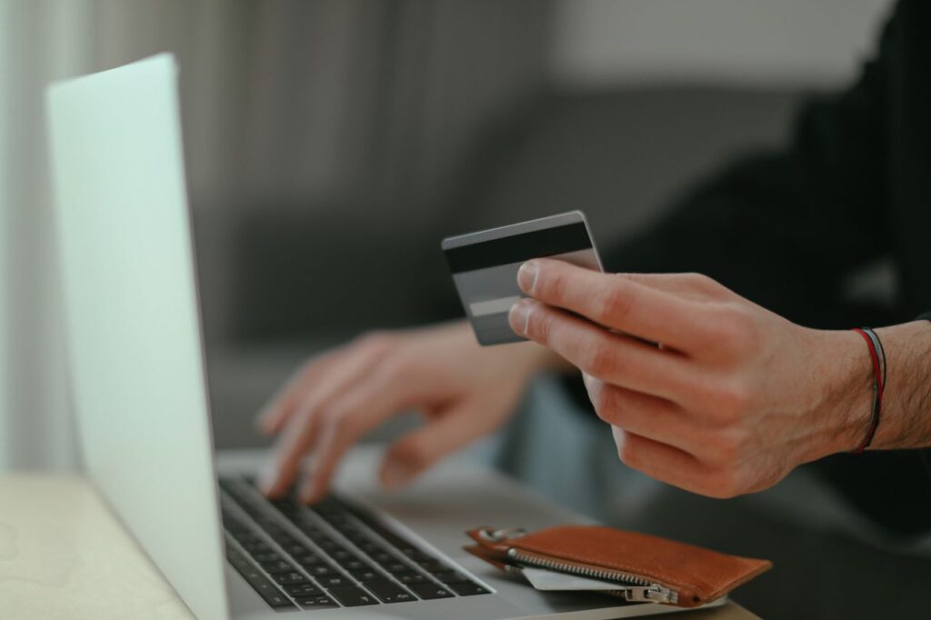Hạn Mức Đi Kèm Phiền Phức Close-up of a person holding a credit card while shopping online on a laptop.